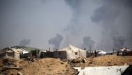 Tents of displaced Palestinians stand in the Nuseirat refugee camp in the central Gaza Strip, as plumes of smoke rise during Israeli bombardment above Gaza City, on September 19, 2025. (Photo by Eyad BABA / AFP)
