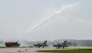 A firefighter gives a water cannon salute to India's MiG-21 fighter jets during their farewell ceremony at the Chandigarh Air Force Station in Chandigarh on September 26, 2025. (Photo by AFP)
