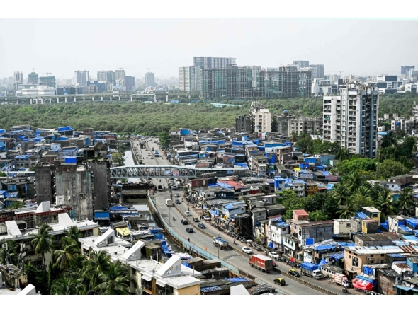 This photograph taken on July 12, 2025 shows high-rise buildings around the cramped shanties of Dharavi, a slum settlement in Mumbai. (Photo by Indranil Mukherjee / AFP)