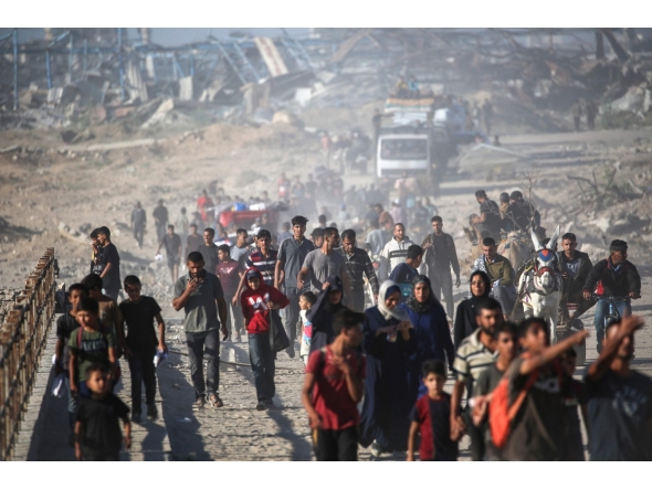 Palestinians walk along the “Netzarim corridor” in central Gaza yesterday to return to their homes. (AFP)