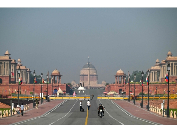 People walk past Kartavya Path near India's presidential palace (Rashtrapati Bhavan) in New Delhi on October 14, 2025. (Photo by Arun Sankar / AFP)
