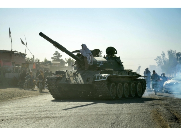 Taliban security personnel on a Soviet-era tank are followed by motorcyclists as they ride towards the border, as clashes take place between Taliban security personnel and Pakistani border forces, in the Spin Boldak district of Kandahar Province on October 15, 2025. (Photo by Sanaullah SEIAM / AFP)

