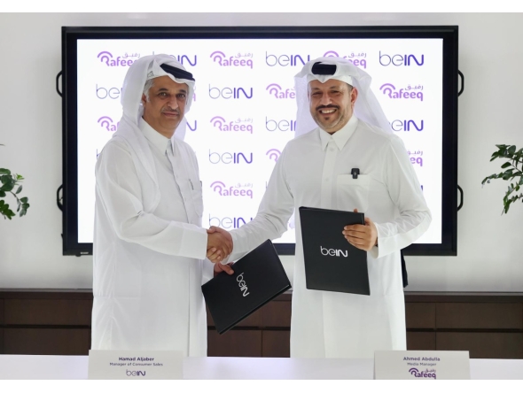 beIN Consumer Sales Manager Hamad Aljaber and Rafeeq Media Manager Ahmed Abdulla exchange documents during the ceremony. 