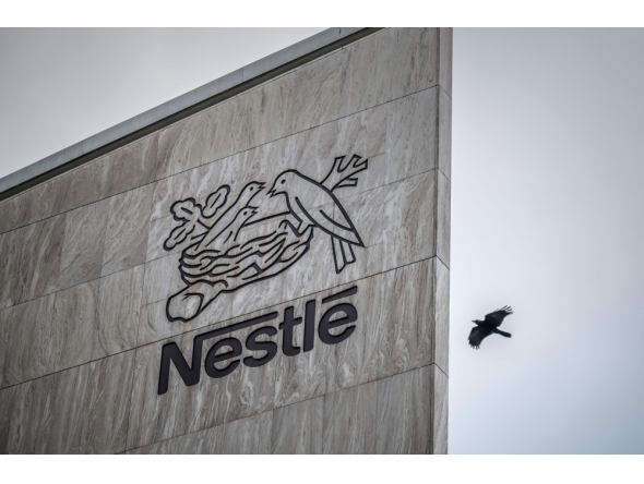 This photograph shows a bird flying next to the logo of Swiss food giant Nestle on the facade of its headquarters, in Vevey, western Switzerland, on October 14, 2025. (Photo by Fabrice Coffrini / AFP)