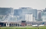 An aircraft prepares to take off as smoke rises from the fire-damaged cargo terminal of Hazrat Shahjalal International Airport in Dhaka on October 19, 2025, a day after the blaze. Photo by Munir UZ ZAMAN / AFP