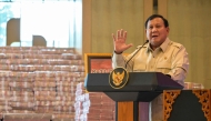 Indonesian President Prabowo Subianto speaks beside stacks of banknotes on October 20, 2025. Photo by Bay Ismoyo / AFP