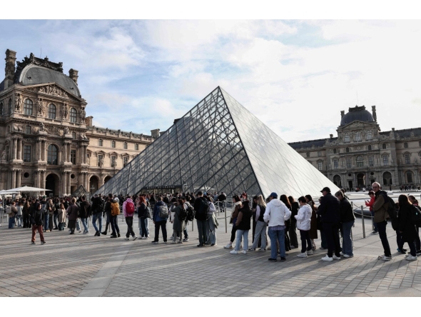 Visitors queue in front of the Pyramide du Louvre, designed by Chinese-US architect Ieoh Ming Pei, with the Louvre Museum in the background in Paris on October 22, 2025. (Photo by Thibaud MORITZ / AFP)
