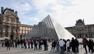 Visitors queue in front of the Pyramide du Louvre, designed by Chinese-US architect Ieoh Ming Pei, with the Louvre Museum in the background in Paris on October 22, 2025. (Photo by Thibaud MORITZ / AFP)