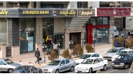 (Files) Iranians walk past an Ayandeh Bank branch (L) in the capital Tehran on January 14, 2017. (Photo by Atta Kenare / AFP)