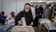A voter casts her ballot while others queue at the Maundi voting centre in Stone Town on October 29, 2025, during Tanzania's presidential elections. Photo by Marco Longari / AFP