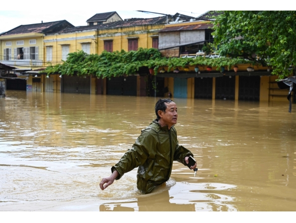 A man wades through a flooded street following heavy rains in Hoi An on October 30, 2025.  Photo by Nhac Nguyen / AFP