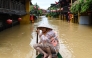 A woman rows a boat on a flooded street following heavy rains in Hoi An on October 30, 2025. (Photo by NHAC NGUYEN / AFP)