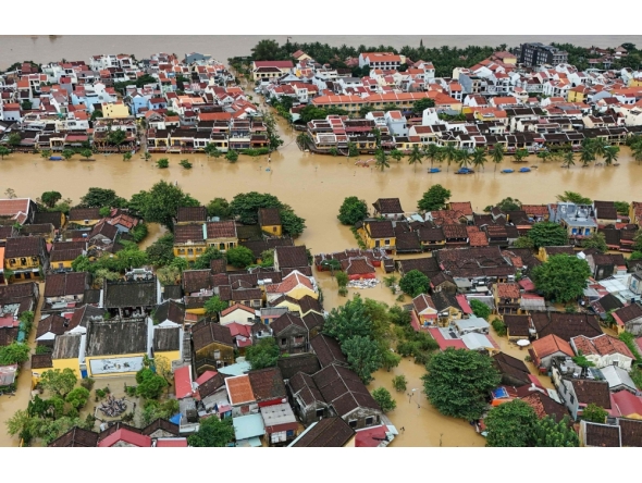 (Files) This aerial picture shows floodwaters inundating streets and buildings following heavy rains in Hoi An on October 30, 2025. (Photo by NHAC NGUYEN / AFP)