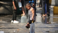A Palestinian boy carries a large plastic bottle filled with water, after collecting it at a camp for displaced people in the Nuseirat refugee camp, located in the central Gaza Strip, on November 2, 2025. (Photo by Eyad Baba / AFP)
