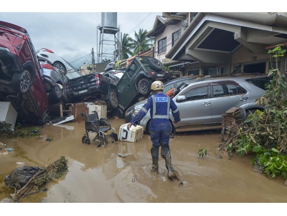 A rescuer walks past piled up cars washed away by floods at the height of Typhoon Kalmaegi in a subdivision of Cebu City in the central Philippines on November 4, 2025. Photo by Alan Tangcawan / AFP