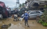 A rescuer walks past piled up cars washed away by floods at the height of Typhoon Kalmaegi in a subdivision of Cebu City in the central Philippines on November 4, 2025. (Photo by Alan Tangcawan / AFP)