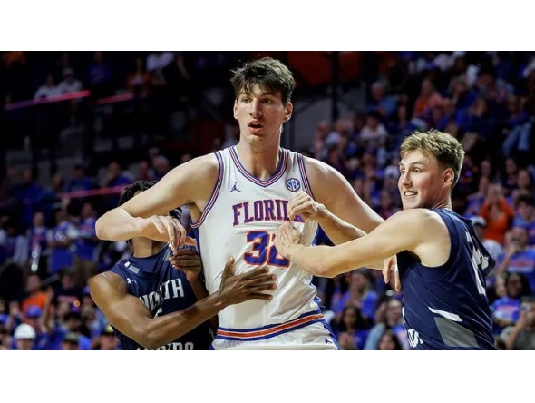 North Florida guard Dante Oliver, left, and North Florida forward Nestor Dyachok, right, guard against Florida center Olivier Rioux, center, in Gainesville, Florida. Chris Watkins/AP Photo