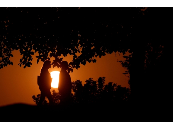 People are silhouetted by the setting sun as they walk in Doha on November 9, 2025. (Photo by Karim Jaafar / AFP)