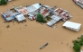 Aerial photo shows a resident paddles his boat in the flood waters past inundated houses in Tuguegarao City, Cagayan province, north of Manila on November 10, 2025. (Photo by John Dimain / AFP)