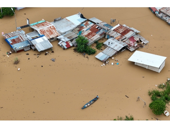 This aerial photo shows a resident paddles his boat in the flood waters past inundated houses in Tuguegarao City, Cagayan province, north of Manila on November 10, 2025, after a river overflowed following heavy rains brought about by Super Typhoon Fung-wong. Photo by JOHN DIMAIN / AFP