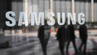 People walk past the Samsung logo displayed on a glass door at the company's Seocho building in Seoul on April 30, 2025. Photo by Jung Yeon-je / AFP
