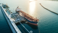 An aerial view of a large oil tanker docked at a pier in the port in process of loading.