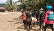 This handout image taken on November 30, 2025 and released on December 1, 2025 by Indonesia's National Search and Rescue Agency (Basarnas) shows military and rescue personnel carrying the body of a flood victim in Batangtoru, South Tapanuli, North Sumatra. (Photo by Handout / BASARNAS / AFP) 