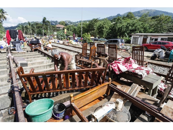 A flood victim restores his belongings in the aftermath of Cyclone Ditwah, along railway tracks in Kandy on December 6, 2025. (Photo by AFP)