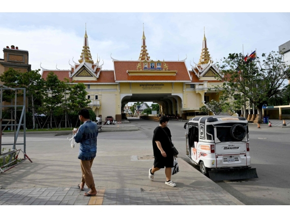 People walk near the closed Poipet International border checkpoint between Cambodia and Thailand in Poipet, Banteay Meanchey province on December 12, 2025, amid clashes along the Cambodia-Thailand border. (Photo by TANG CHHIN Sothy / AFP)
