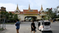 People walk near the closed Poipet International border checkpoint between Cambodia and Thailand in Poipet, Banteay Meanchey province on December 12, 2025, amid clashes along the Cambodia-Thailand border. (Photo by TANG CHHIN Sothy / AFP)
