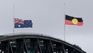 The Australian and Aboriginal flags fly at half-mast on the Sydney Harbour Bridge in the aftermath of the Bondi Beach shootings, in Sydney on December 15, 2025. (Photo by David Gray / AFP)