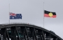 The Australian and Aboriginal flags fly at half-mast on the Sydney Harbour Bridge in the aftermath of the Bondi Beach shootings, in Sydney on December 15, 2025. (Photo by David Gray / AFP)