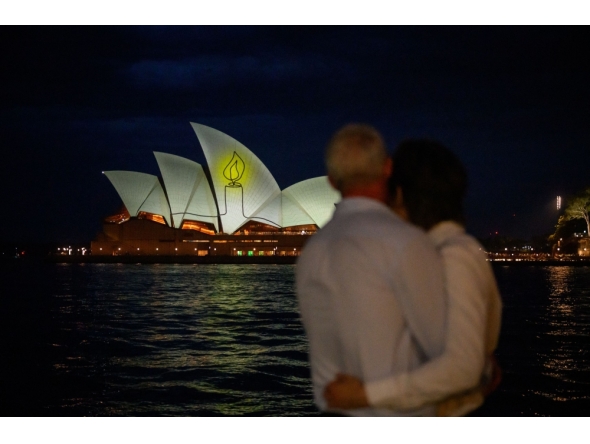 The Sydney Opera House is illuminated with candlelights in Sydney on December 21, 2025, as part of a national day of reflection honouring the victims of the Bondi Beach terrorist attack. (Photo by George Chan / AFP)