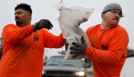 Los Angeles County workers load sandbags for a resident, near the Eaton Fire burn zone, in preparation for a strong atmospheric river storm arriving today to the region on December 23, 2025 in Altadena, California. Photo by Mario Tama/Getty Images/AFP 