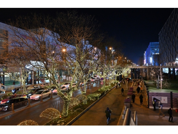 People walk next to shopping centers in Beijing on December 19, 2025. (Photo by Adek BERRY / AFP)
