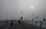 Commuters ride along the Signature Bridge over Yamuna river amid dense smog in NEW DELHI on December 27, 2025. (Photo by Arun SANKAR / AFP)