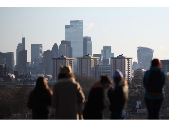 People look out at the view of the skyline of the financial office buildings in the City of London from Primrose Hill in London on January 2, 2026. Photo by HENRY NICHOLLS / AFP