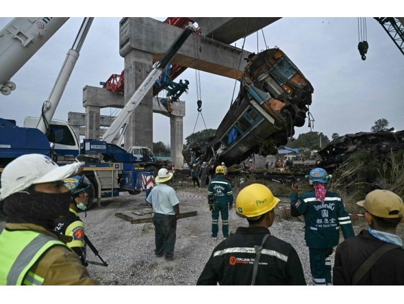 Recovery workers watch as a carriage of a train that crashed when a construction crane collapsed is lifted off the tracks in Thailand's Nakhon Ratchasima province on January 14, 2026. (Photo by Lillian Suwanrumpha / AFP)
 