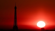 (Files) The sun rises by the Eiffel Tower in Paris on July 1, 2025. (Photo by Thibaud Moritz / AFP)
 