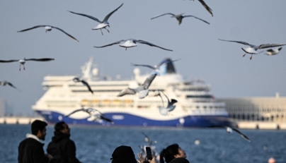A woman uses her mobile phone to take pictures of the seagulls at the old seaport in Doha on January 20, 2026. (Photo by MAHMUD HAMS / AFP)
