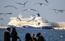 A woman uses her mobile phone to take pictures of the seagulls at the old seaport in Doha on January 20, 2026. (Photo by MAHMUD HAMS / AFP)
