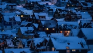 Houses along the coastline are lit as early morning light breaks over the snow-covered hills in Nuuk, Greenland, on January 22, 2026. (Photo by Jonathan NACKSTRAND / AFP)