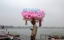 A cotton candy vendor uses his mobile phone as he waits for customers along the banks of the river Ganges in Varanasi on January 29, 2026. (Photo by Niharika KULKARNI / AFP)