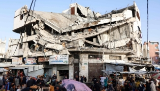 Palestinians shop for food beneath a destroyed building in Gaza City's Zawiya market on February 18, 2026, on the first days of the holy fasting month of Ramadan. (Photo by Omar AL-QATTAA / AFP)
