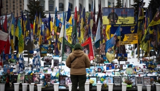 A person stands at a makeshift memorial to fallen Ukrainian and foreign soldiers in Independence Square in Kyiv on February 23, 2026. (Photo by HENRY NICHOLLS / AFP)