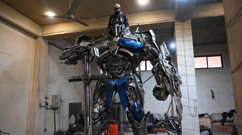 This photograph shows a worker weilding scrap metal into Optimus Prime, a film character from Transformers, at a studio on the outskirts of Islamabad. Sparks fly and metal groans in a cavernous workshop on the outskirts of Islamabad, where Pakistani artist Ehtisham Jadoon fuses discarded car parts into colossal pieces inspired by 