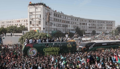 (Files) Supporters cheer as the Senegalese football players ride on a bus during a trophy parade in the streets of Dakar on January 20, 2026. (Photo by Guy Peterson / AFP)