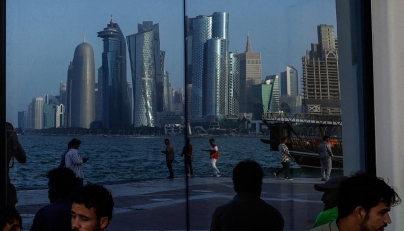 People sit with the reflection of the Doha skyline along the Doha Corniche, on the second day of Eid al-Fitr celebrations marking the end of the Muslim holy month of Ramadan, in Doha on March 21, 2026. Photo by AFP