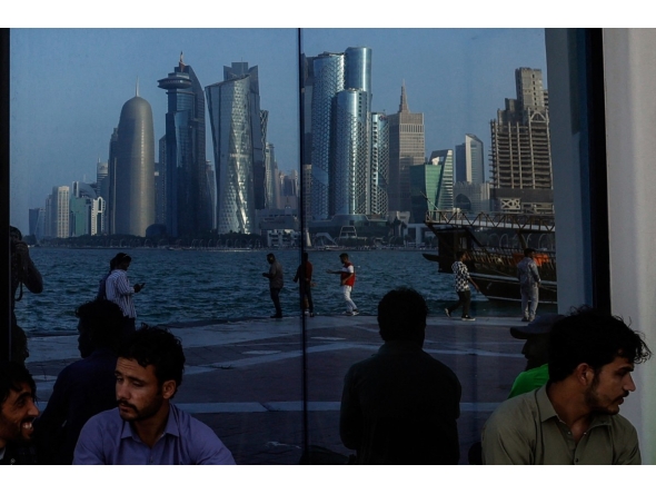 People sit with the reflection of the Doha skyline along the Doha Corniche, on the second day of Eid al-Fitr celebrations marking the end of the Muslim holy month of Ramadan, in Doha on March 21, 2026. Photo by AFP