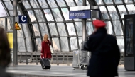 A traveller with suitcase and a train conductor walk along a platform at the main train station (Hauptbahnhof) in Berlin on March 27, 2026. Photo by RALF HIRSCHBERGER / AFP